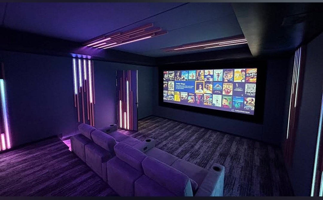Home cinema with acoustic wall panels and recliner seating by YHWH VISION